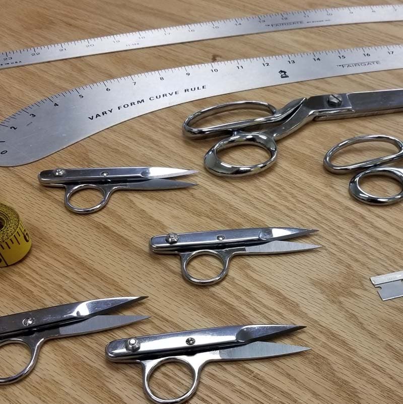 Gingher brand seamstress and tailoring tools - scissors, curved rules, tape measures, thread nippers.